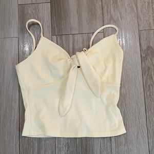 Cream/light yellow colored tank top with a tie bow